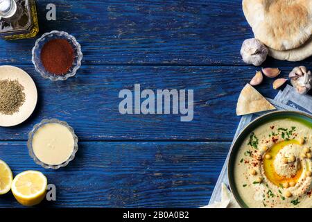Chickpea hummus and various middle-eastern vegetarian ingredients on a dark blue wooden background Stock Photo