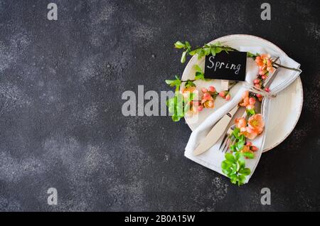 Festive table place setting with spring blossoming branch on a dark concrete background. Copy space Stock Photo