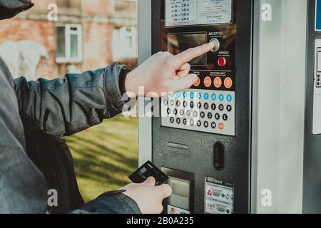 man pays for parking with a credit card with NFS technology. Easy payment. Process of paying in machine parking terminal. Payment for parking in the Stock Photo