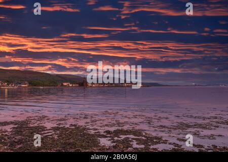 Largs Looking South into the town at sunset with the sunset reflections on the town seafront. A good holiday touristic image. Stock Photo