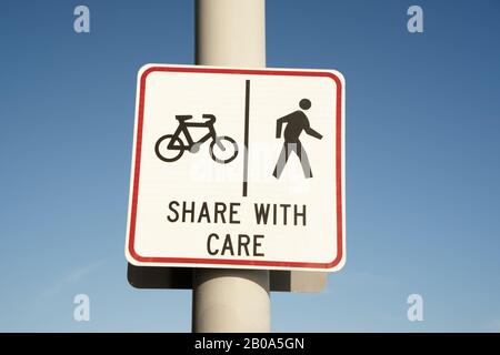 A warning sign on a shared pathway along the seafront in Mission Bay, an affluent Eastern Bay suburb of Auckland, New Zealand. Stock Photo