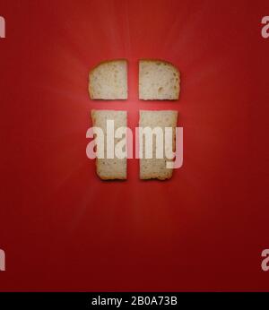 Our daily bread, a metaphor and sign. Cross, Christian values, Christian religion concept. Bread in the form of a cross on a red background, top view Stock Photo