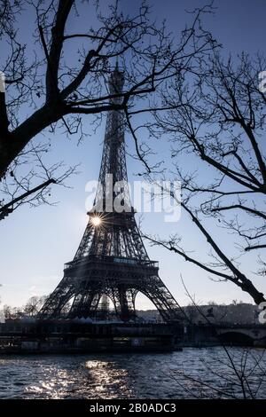 The sun rises behind the Eiffel Tower on the Seine River, Paris Stock Photo