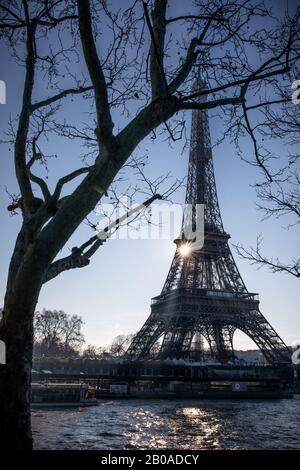 The sun rises behind the Eiffel Tower on the Seine River, Paris Stock Photo