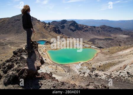 One male hiker, on top of rock, looking at Emerald Lakes, Tongariro Stock Photo