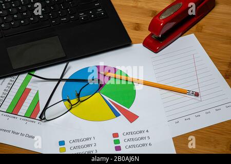 Desktop Business workspace with a laptop, a #2 pencil and Stapler and some paperwork with generic business graphs.  There is some room for copy and pa Stock Photo