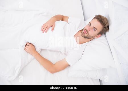 Causes of early morning headache. Migraine headaches. Sleep problems can lead to headaches in morning. Handsome man relaxing in bed. Snoring can increase risk headaches. Common symptom of sleep apnea. Stock Photo