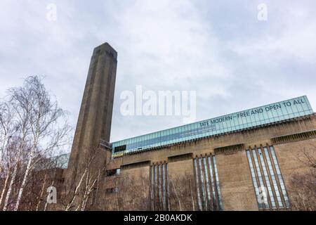 View of the exterior and iconic chimney of Tate Modern art gallery, Bankside, London SE1 on South Bank Embankment of the River Thames in bad weather Stock Photo