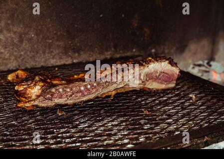 Traditional suckling pig cooked on the charcoal grill. The little pig is roasted whole on an open fire. Organic pig on the spit. Stock Photo