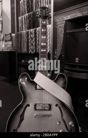 Electric acoustic guitar and speakers Musical Instruments as black and white still life pictures in a bespoke menswear store with shirts and neckties Stock Photo