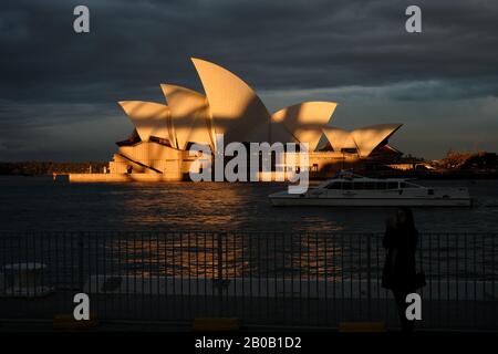 Sydney Opera House in golden late afternoon sunlight with shadow lines cast over the white sails from the Harbour Bridge as seen from campbells cove Stock Photo