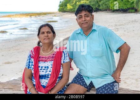Beautiful photo of happy, middle aged Indian couple spending holidays at tropical island. Female wearing ethnic Indian attire and male in casual. Stock Photo