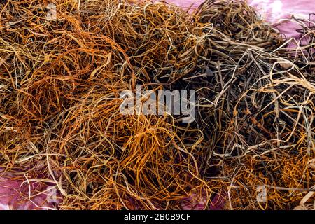 Tangled threads abstract texture pattern background. Big pile of natural weaving thread ropes scattered randomly like spaghetti on carpet. Craft weaving workshop. Stock Photo