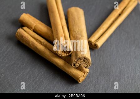 Cinnamon sticks isolated on black slate background with selective focus - close up horizontal image of cinnamon spice Stock Photo