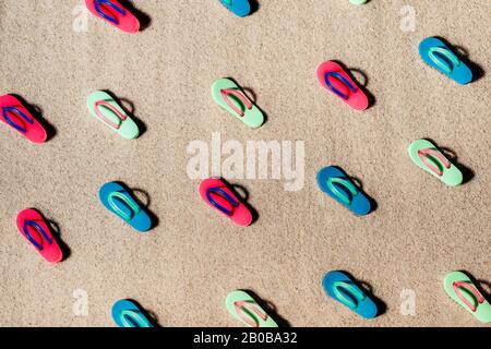 Pattern of beach colorful sandals or thongs on a sandy beach. Stock Photo