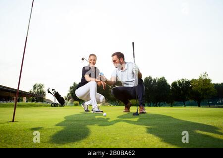 A handsome man is explaining something to his beautiful girlfriend about golf. Stock Photo