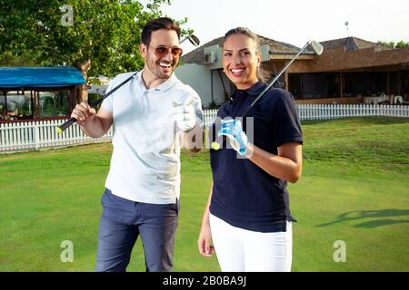 Male and female golfers are smiling on a golf course. Stock Photo