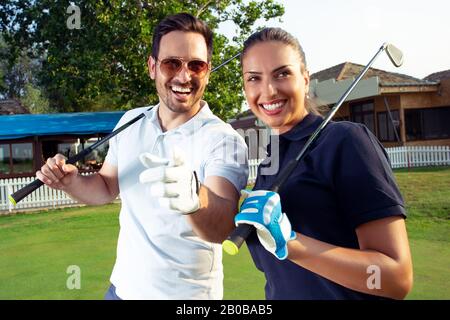 A beautiful couple is posing for a photo on a golf course. Stock Photo
