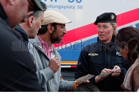 A helpful German police woman explains how to use transport tickets to newly arrived refugees outside Munich Central station in 2015.