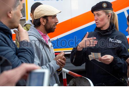 A helpful German police woman explains how to use transport tickets to newly arrived refugees outside Munich Central station in 2015.