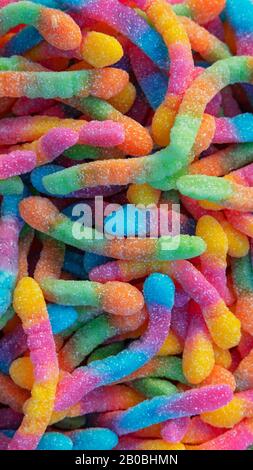 Pile of neon sugary gummy worms or  chewy sour crawlers background. Close-up of colorful and flavorsome sweet and sour treats coated in sugar crystals Stock Photo
