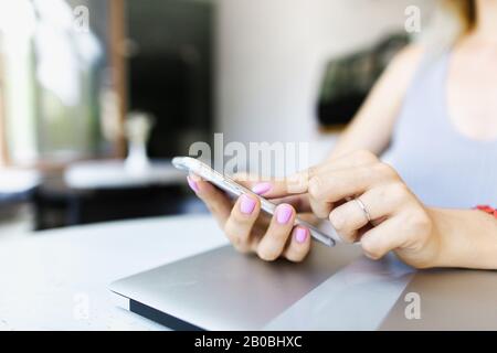 Close up hands chatting by smartphone near closed laptop. Stock Photo
