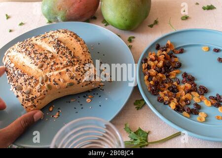 horizontal shot of hand picking paved bread with plate of resins Stock Photo