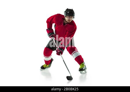 Activity. Male hockey player with the stick on ice court and white background. Sportsman wearing equipment and helmet practicing. Concept of sport, healthy lifestyle, motion, movement, action. Stock Photo