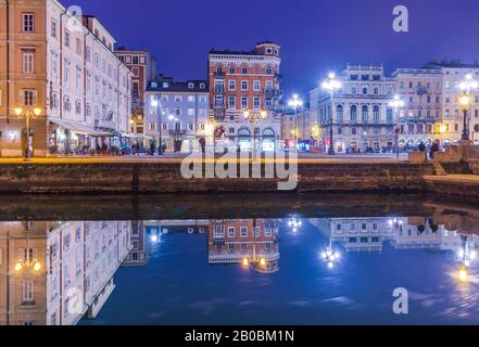 Trieste - December 2016, Italy: Night view of Trieste, old buildings mirror reflected in water, Grand Canal in Trieste city center Stock Photo