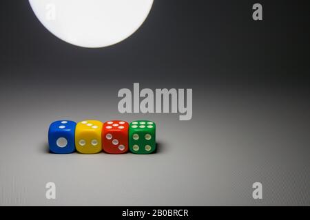 color dice with numbers on grey background with light from a lamp Stock Photo