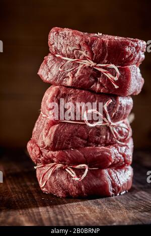 Three raw medallions of thick juicy fillet steak stacked on top of one another in a close up side view Stock Photo