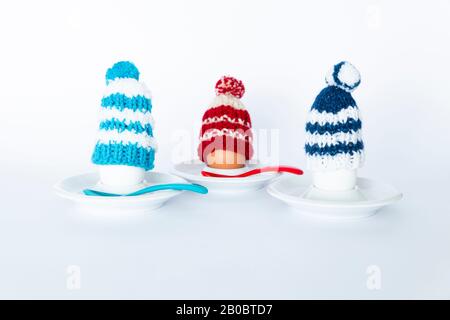 Fun breakfast concept with boiled eggs wearing knitted woolen hats on white background Stock Photo