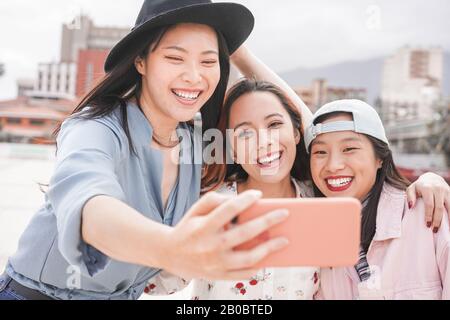 Trendy asian girls making video story for social network app outdoor - Young women friends having fun taking selfie - New technology trends and friend Stock Photo