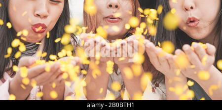 Happy asian friends having fun throwing confetti at party outdoor - Young trendy people enjoying fest event - Hangout, friendship, trends and youth co Stock Photo