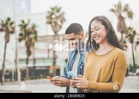 Latin couple shopping online using smartphone app - Young people having fun with new e-commerce technology trend - Social network, tech and millennial Stock Photo