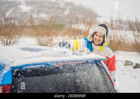 Removing snow from car with a brush Stock Photo
