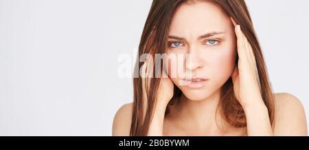 Young pretty girl with migraine. Headache woman pain. Stress sick model portrait. Negative emotion portrait. Sad people. Stock Photo