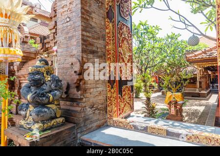 Hindu temple entrance gates with wooden carved doors and dvarapala guardian statue. Canggu, Badung, Bali. Traditional classic Balinese architecture. B Stock Photo