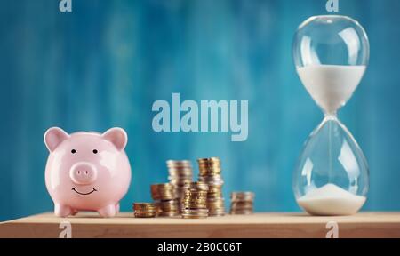 piggy bank with stacked coins and hourglass Stock Photo