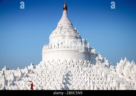 Mingun, Myanmar: Girl in a red dress poses for photos at the Hsinbyume Pagoda. Beautiful architecture, white wavy terraces, deep blue sky Stock Photo