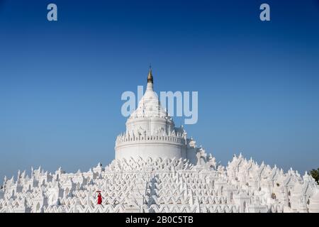 Mingun, Myanmar: Girl in a red dress poses for photos at the Hsinbyume Pagoda. Beautiful architecture, white wavy terraces, deep blue sky Stock Photo