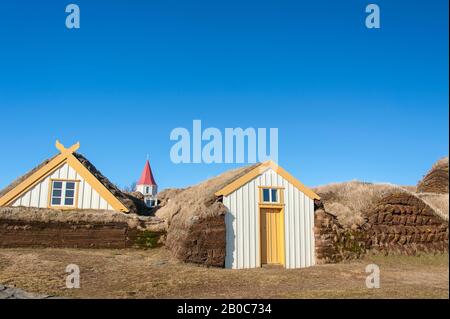 Traditional turf houses of Glaumbauer ethnographic Farm Museum, Skagafjordur, Iceland.  Yellow and white timber houses against clear blue sky backgrou Stock Photo