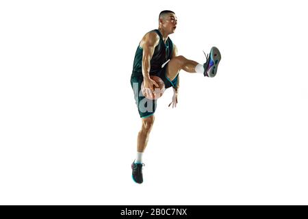 Young basketball player of team wearing sportwear training, practicing in action, motion in jump, flight isolated on white background. Concept of sport, movement, energy and dynamic, healthy lifestyle. Stock Photo
