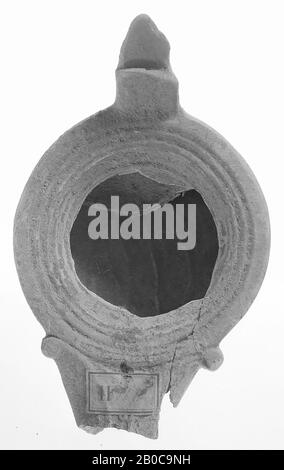 A gray-varnished oil lamp with a round body on a flat base. The concave mirror is surrounded by recessed concentric circles. The short, broad spout is framed with volutes. The vertically attached ear and has a separate shape., Oil lamp, earthenware, terracotta, 4.5 x 11 x 6.7 cm, 2nd century AD. 100-200, Tunisia Stock Photo