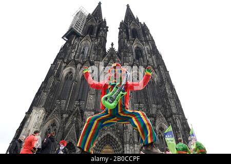 Cologne, Germany. 20th Feb, 2020. A carnival performer dressed as a clown jumps up in front of the Cologne Cathedral. The women's carnival marks the beginning of the street carnival. Credit: Roberto Pfeil/dpa/Alamy Live News Stock Photo