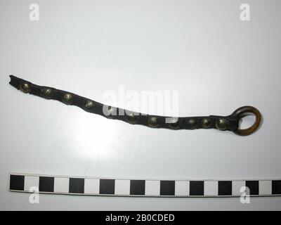 Leather belt with legs ring. The belt has 11 round, gold colored studs with a copper alloy cap and a ring of bone. The decorative nails are as wide as the belt. The end of the belt has been knocked through the ring and secured with a decorative nail. The ring has a smooth inner side, the outside of the buckle carries a horizontal line notch that is interrupted by a vertical notch. There is a round finishing plate under the decorative nails. Length of the belt, including the ring, is 18.2 cm. The diameter of the legs ring is 2.35 cm and the thickness of the ring is 0.4 cm. Diameter of finishing Stock Photo