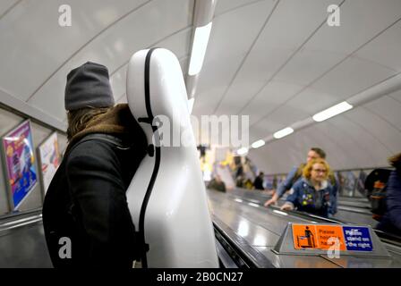 London, England, UK. Man carrying a cello down an escalator in a tube station Stock Photo