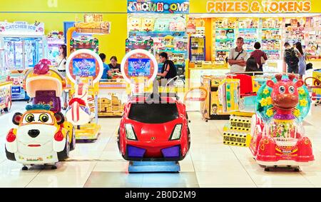 Iloilo City, Philippines: Close-up view of an indoor entertainment playground with colorful toy rides for children, bingo players Stock Photo