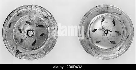 Small disc of silver-plated bronze cast in one piece. Front: in the middle a concave field, around it an engraved groove, then a border first convex than concave, enclosed by a quarry. In the middle a pinhole. Decorated with drooping stems, in the middle 6, 2 on 2 bent together, each ending in a leaf, on the edge from the inside to the outside three times two stems, each ending in a leaf. Rear: undecorated. There is a flat tunnel on it, which also has a pin hole in the middle. Note: the pen is still complete, in its place, in the edge there is a snag-shaped tear., Phalera (appendix), metal Stock Photo