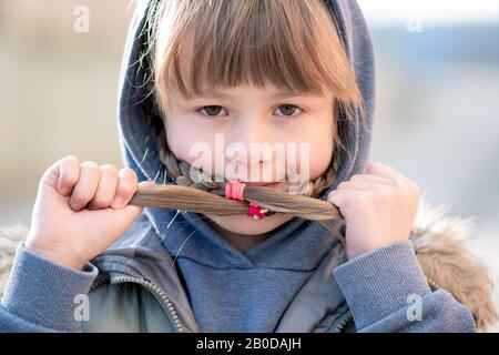 Portrait of happy child girl with hair braids in warm clothes in autumn outdoors. Stock Photo